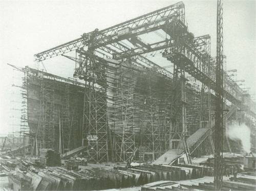 5 августа 1910 г. Покрытие корпуса Титаника стальными листами. Деревянные леса, окружившие корпуса судов, позволяли клепальщикам и другим рабочим верфи, работать над корпусами таких огромных судов. На переднем плане виден склад стальных пластин обшивки